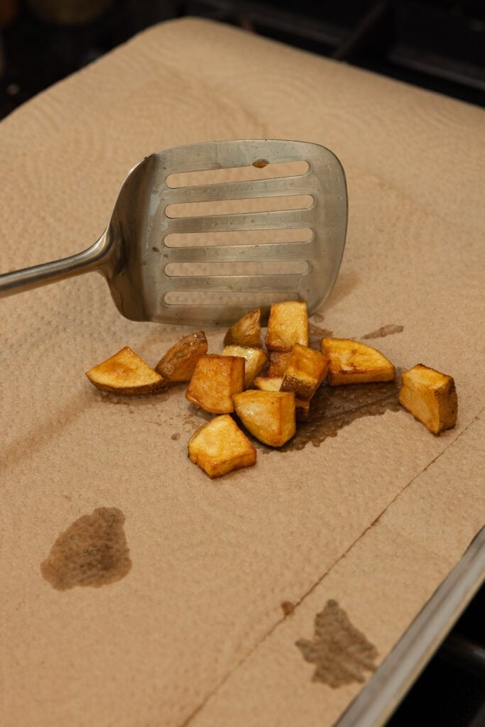 Cooked potatoes being placed on a towel to soak up grease.
