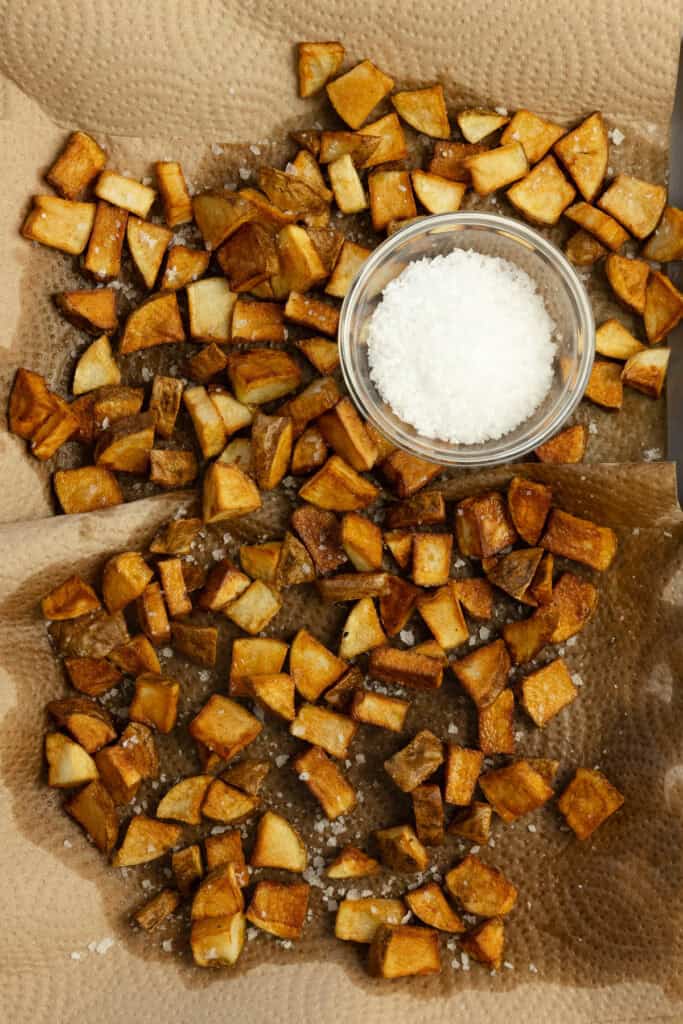 Potatoes on a paper towel with a jar of salt in the middle.
