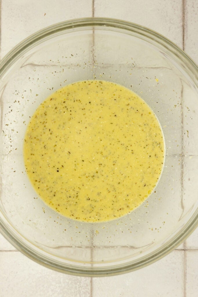 Pasta salad dressing in a glass bowl.
