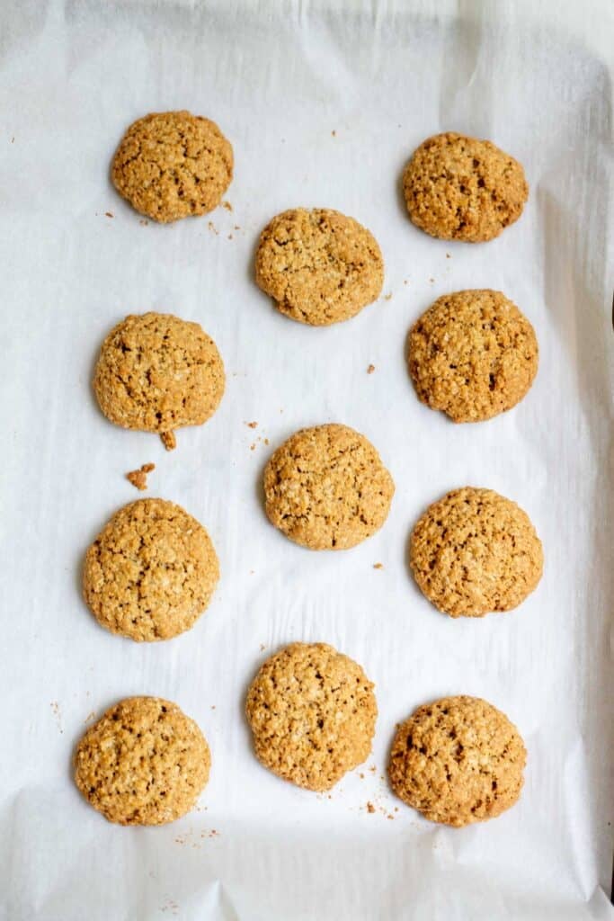 Oatmeal cookies cooling on a parchment lined cookie sheet.