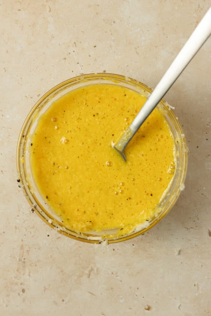Egg yolk mixture in a bowl with a spoon resting in the glass bowl.