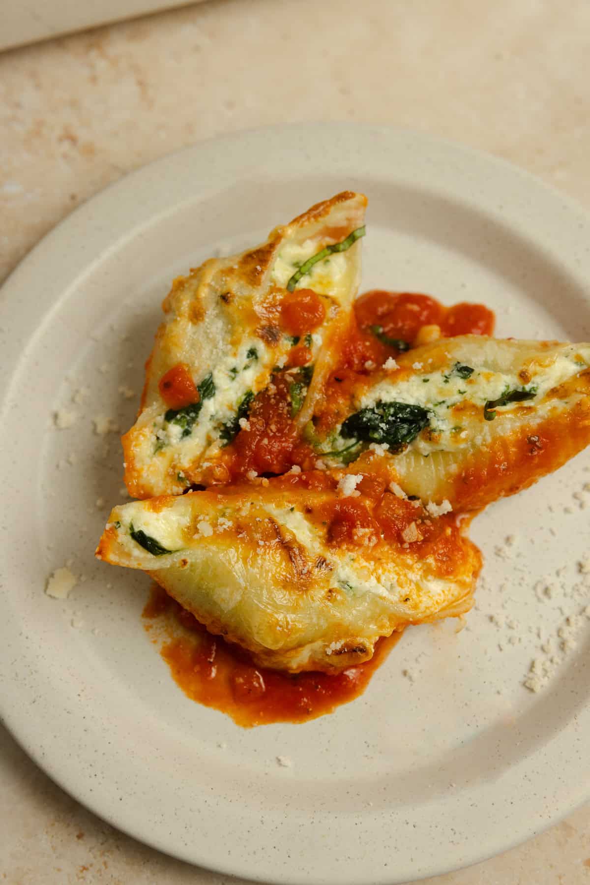Three stuffed ricotta cheese shells served on a white plate.