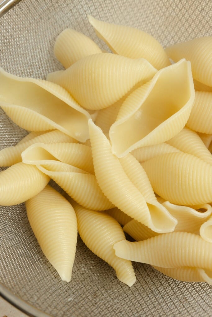 Boiled pasta shells drained from the water in a bowl.