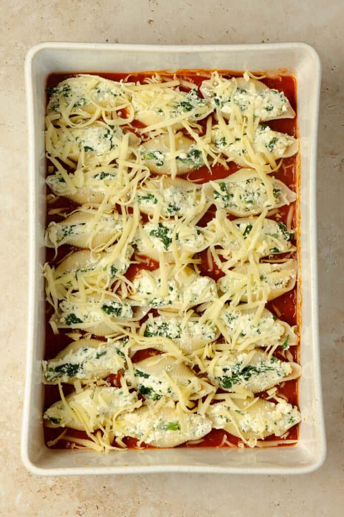 Stuffed jumbo shells covered with mozzarella cheese in a baking dish.