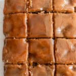 Close up picture of a apple cake topped with caramel glaze cut into squares.