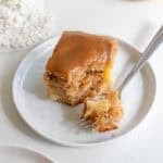 slice of apple cake with a forkful of cake on a white plate.