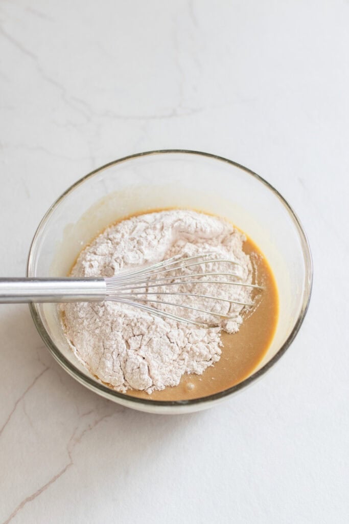 Adding dry ingredients to wet ingredients in a glass bowl.