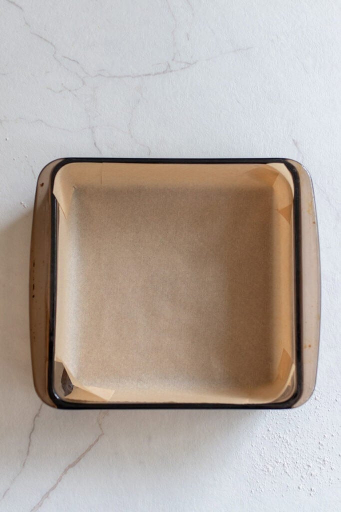 Lining a baking dish with parchment paper. 