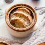 french onion soup topped with baguette slices and melted cheese.