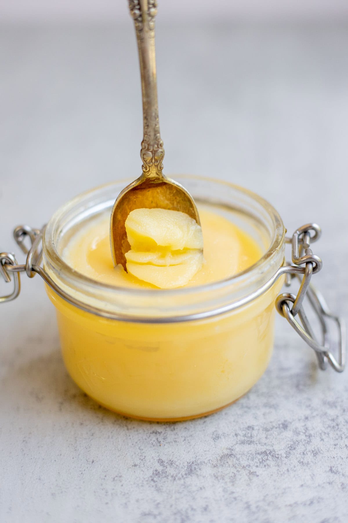 A spoon scooping out ghee from a glass jar.