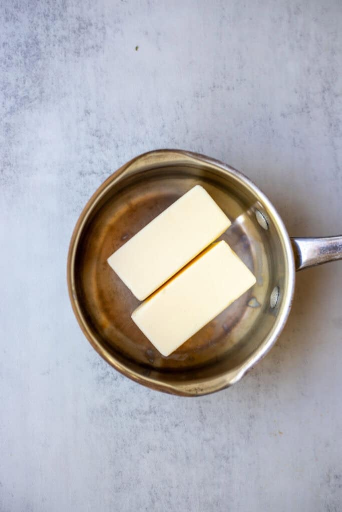 Two sticks of butter in a pot on the stove.