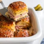 Ham and swiss sliders in a baking dish with one slider on top of the rest of the sliders.