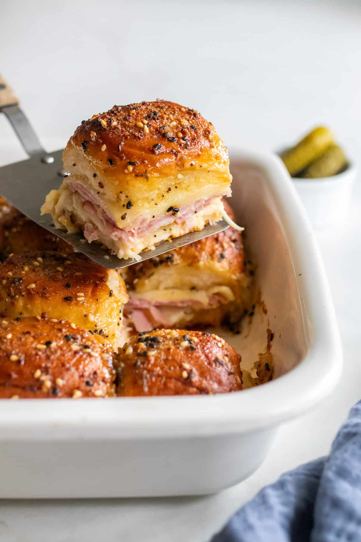 Ham and swiss sliders in a baking dish with one slider on top of the rest of the sliders.