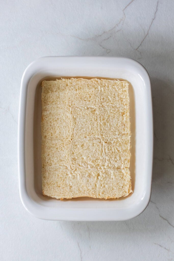 Slider rolls sliced in half in a baking dish.