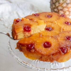 Slice of pineapple sulfide down cake on a glass cake stand.