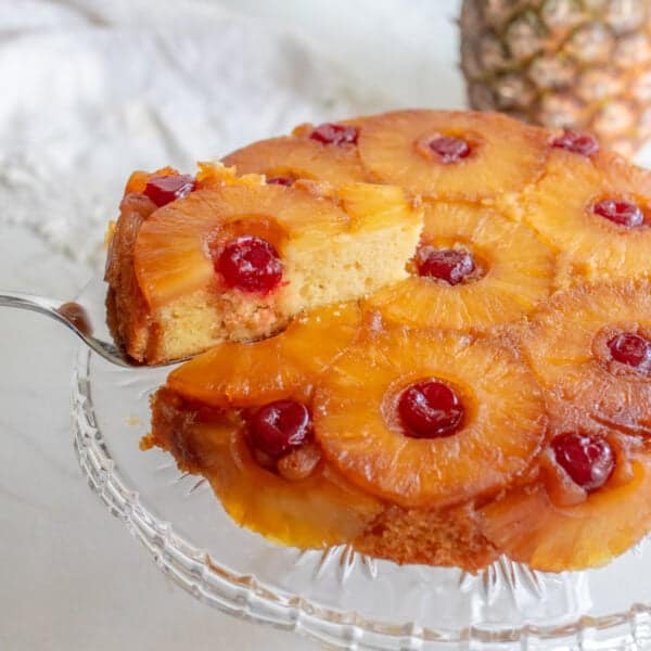 Slice of pineapple sulfide down cake on a glass cake stand.