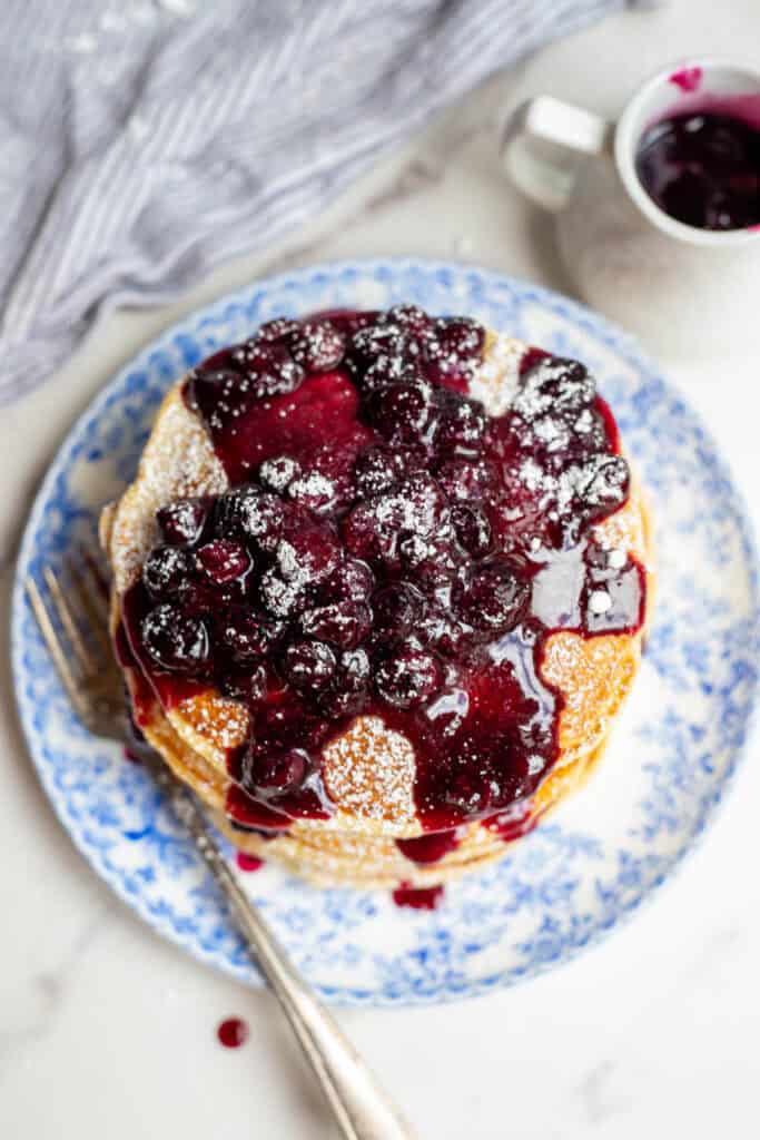Blueberry syrup-covered ricotta pancakes on a plate.