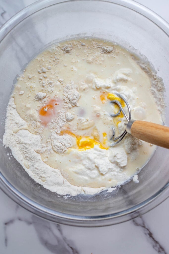 Ricotta cheese and eggs added to a glass mixing bowl. 