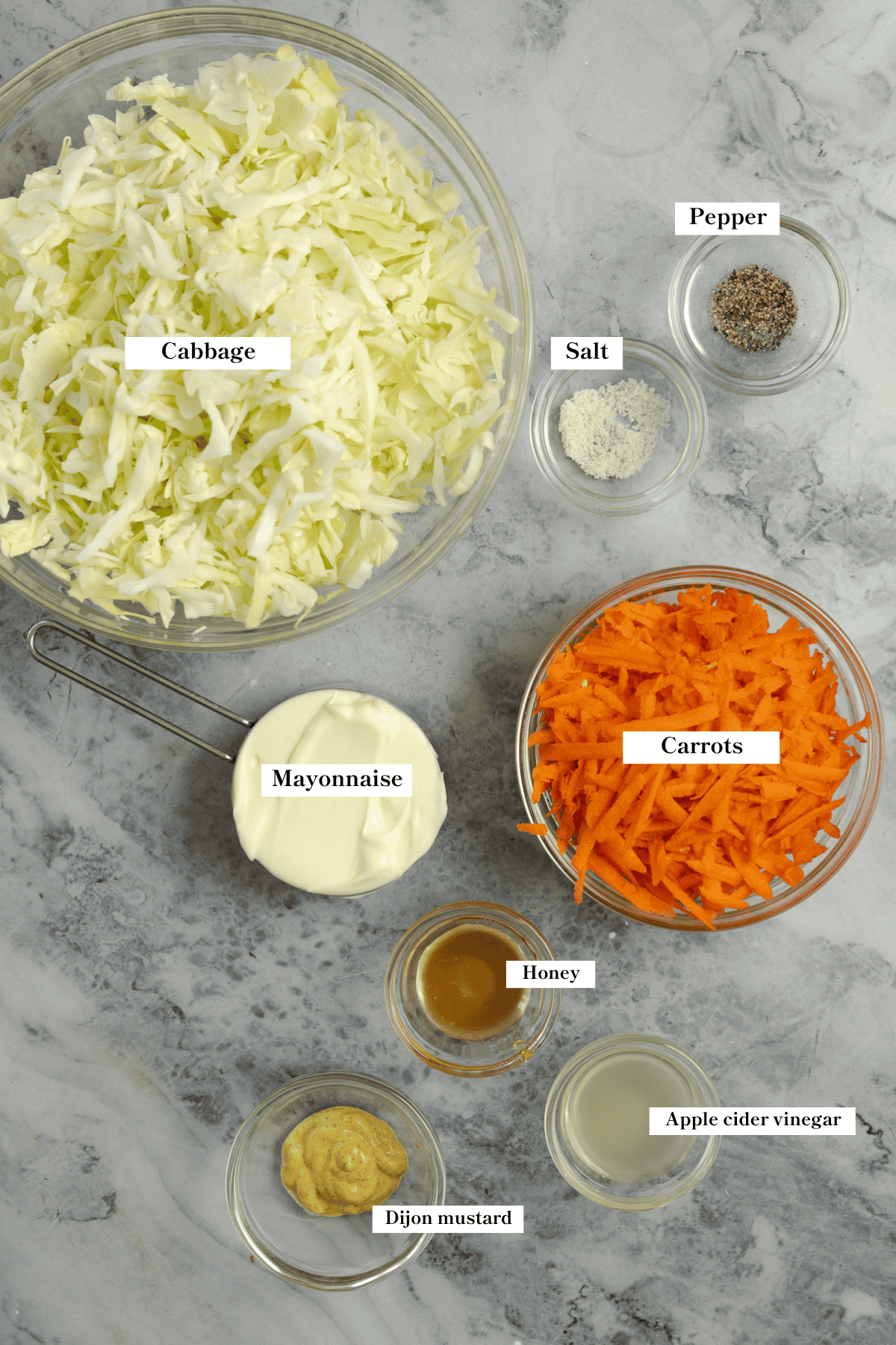 Cabbage, carrots, mayonnaise, and spices on the countertop.