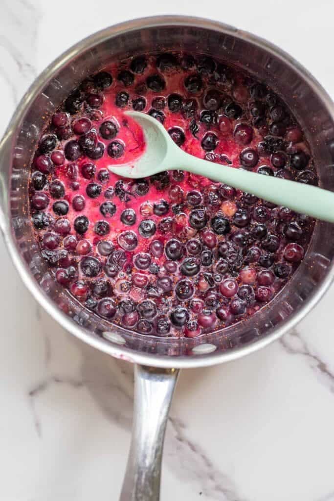 Cornstarch added to a pot of simmering blueberries.