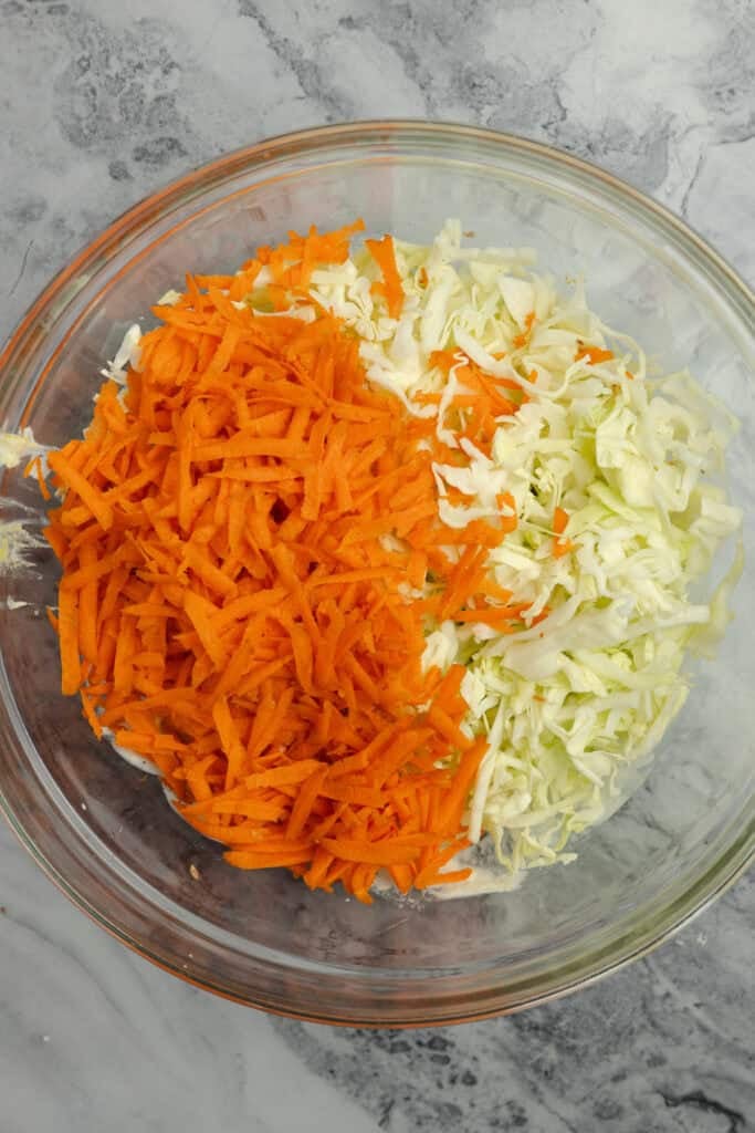 Shredded cabbage and shredded carrots in a glass bowl. 