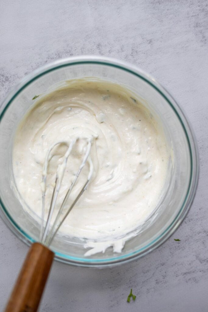 Ranch dip being mixed together with a metal whisk.