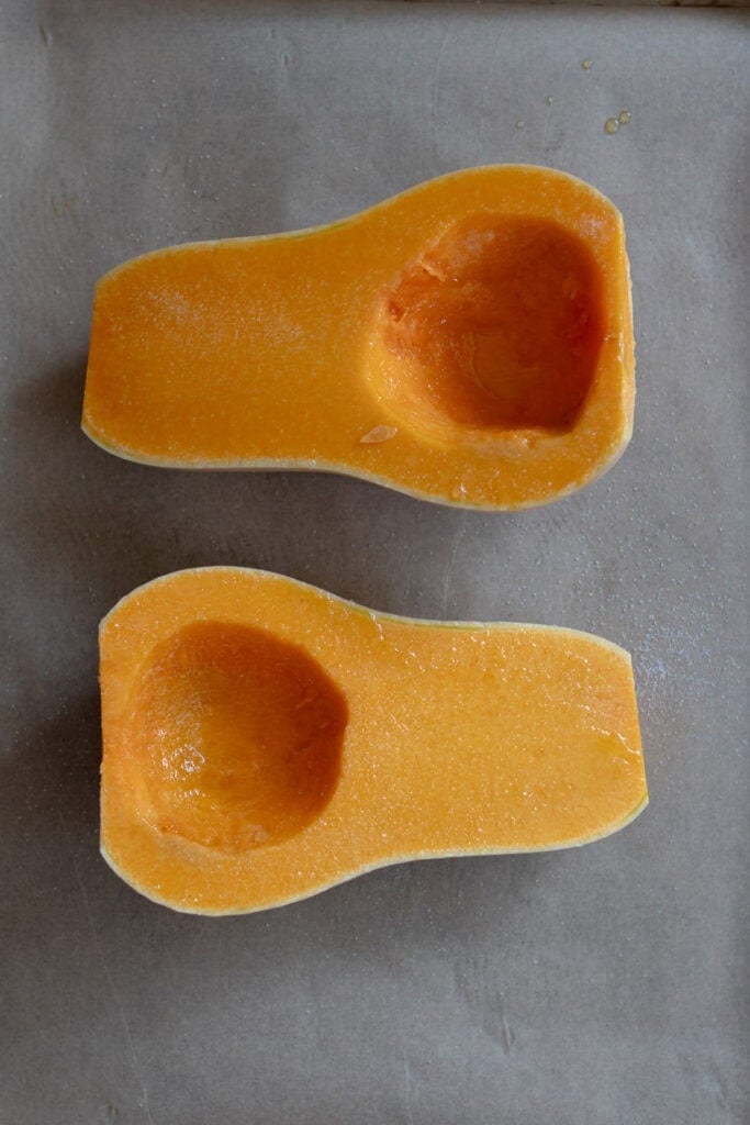 Butternut squash sliced in half on a baking sheet.