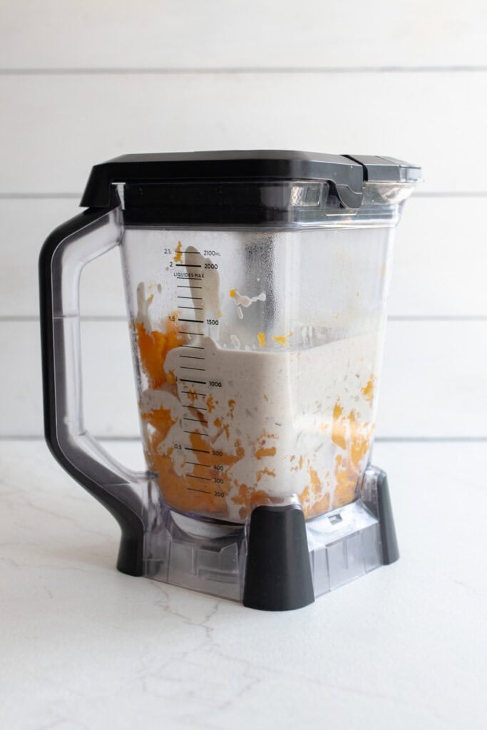 A blender with butternut squash and cream sauce.