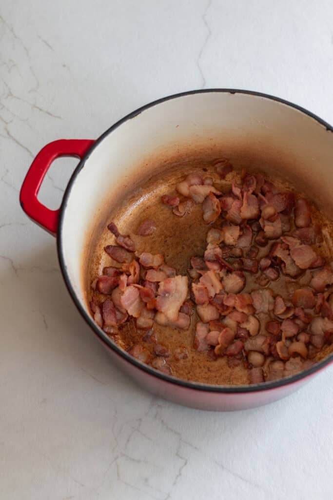 Bacon cooking in a Dutch oven.