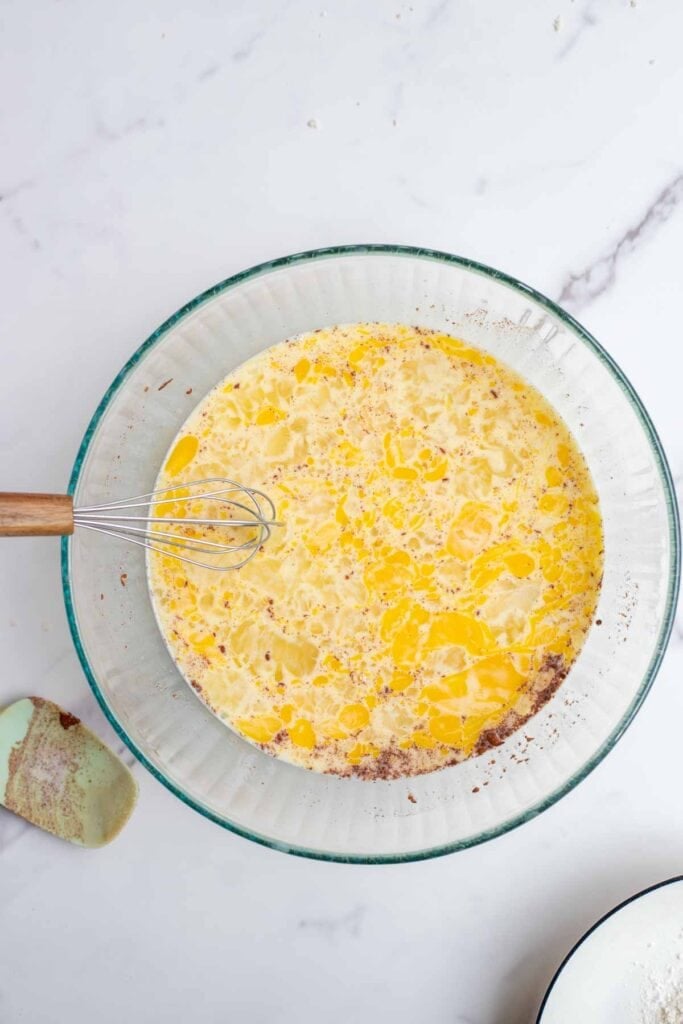 Milk, eggs, cream, sugar, vanilla, and cinnamon mixed into a bowl.