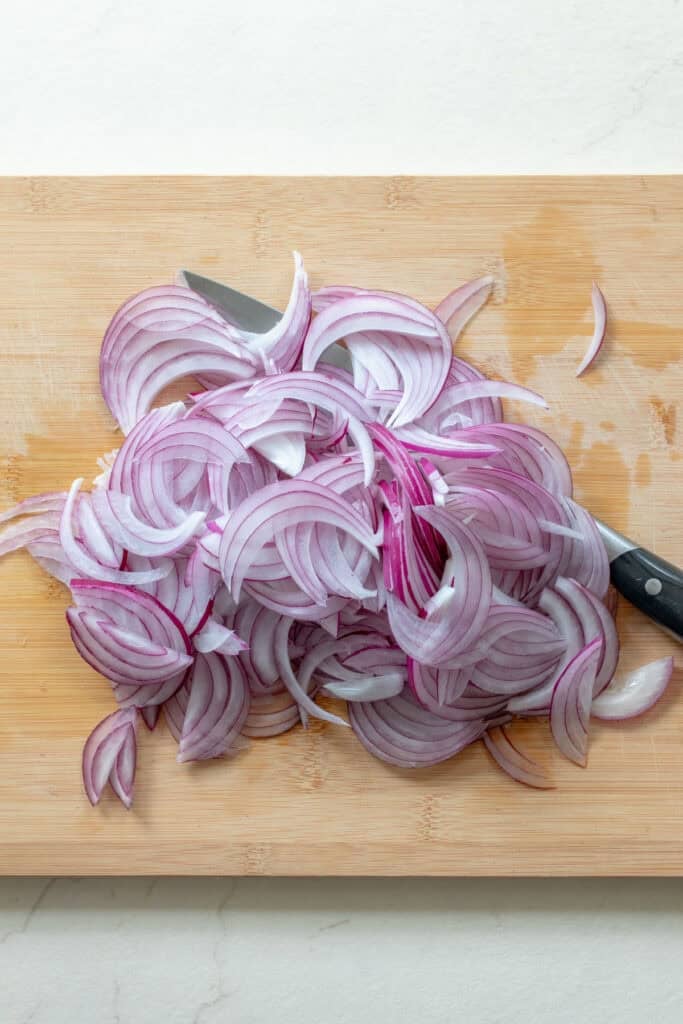 Sliced red onion on a wood cutting board.
