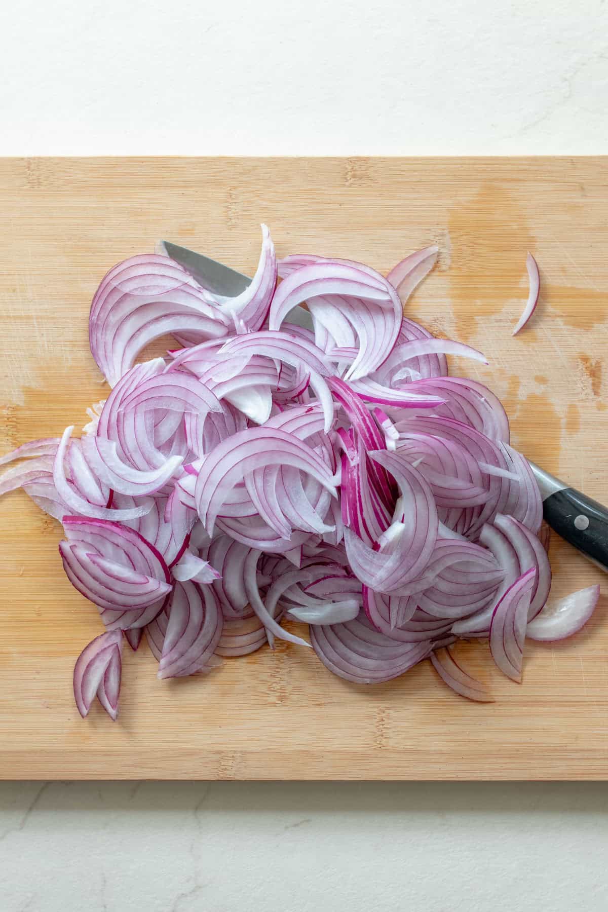 Sliced red onion on a wood cutting board.