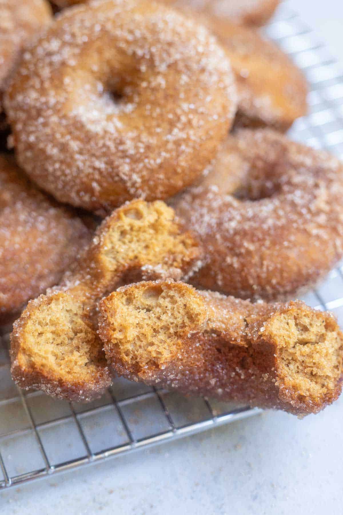 donuts on a cooling rack with one of them split in half.