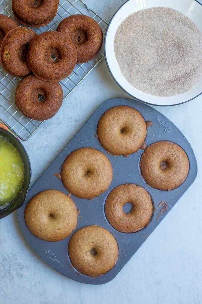 Apple cider donuts baked and cooling in a donut pan.