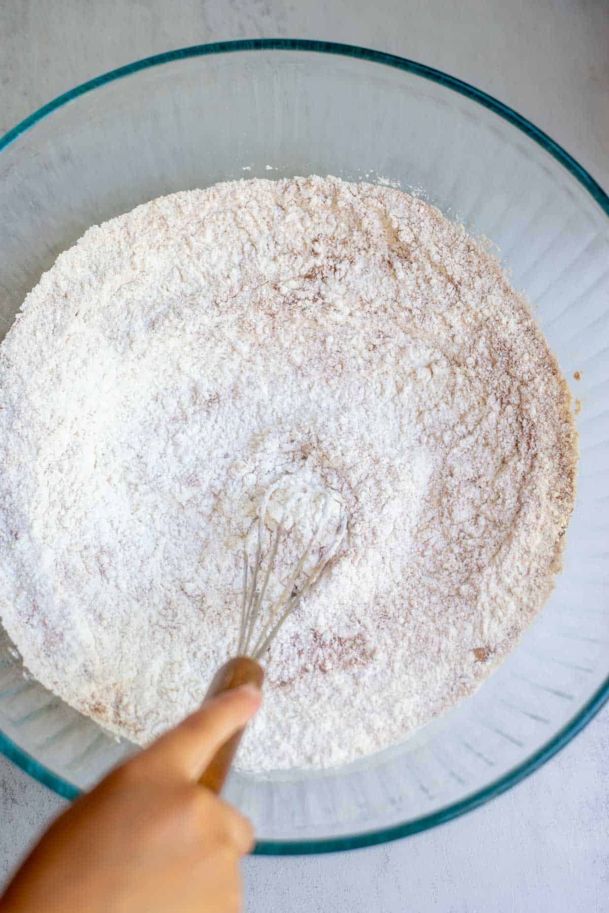 flour, sugar, baking powder, and nutmeg in a glass bowl.