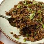 Spoonful of Korean beef coming out of a plate of beef.