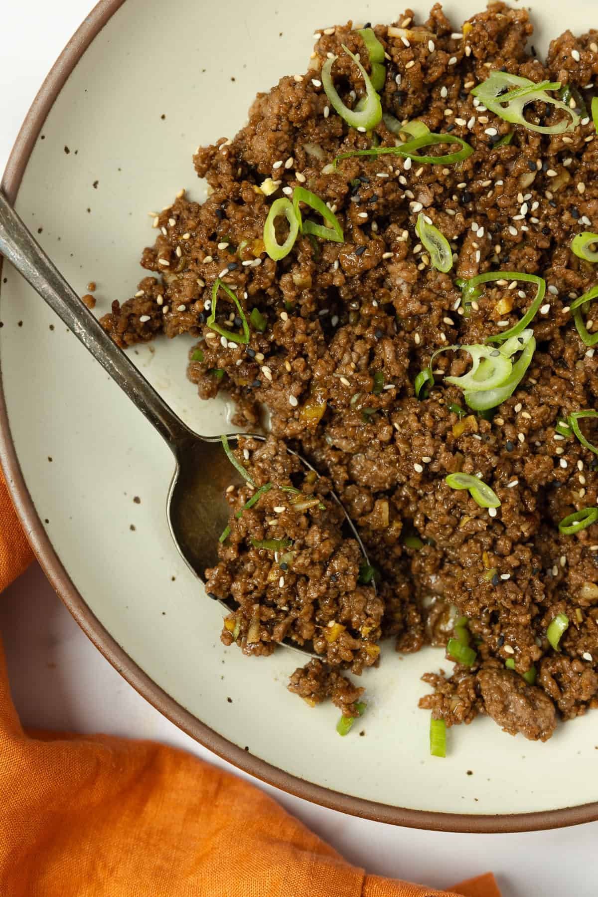 Korean beef topped with sliced green onions in a plate.