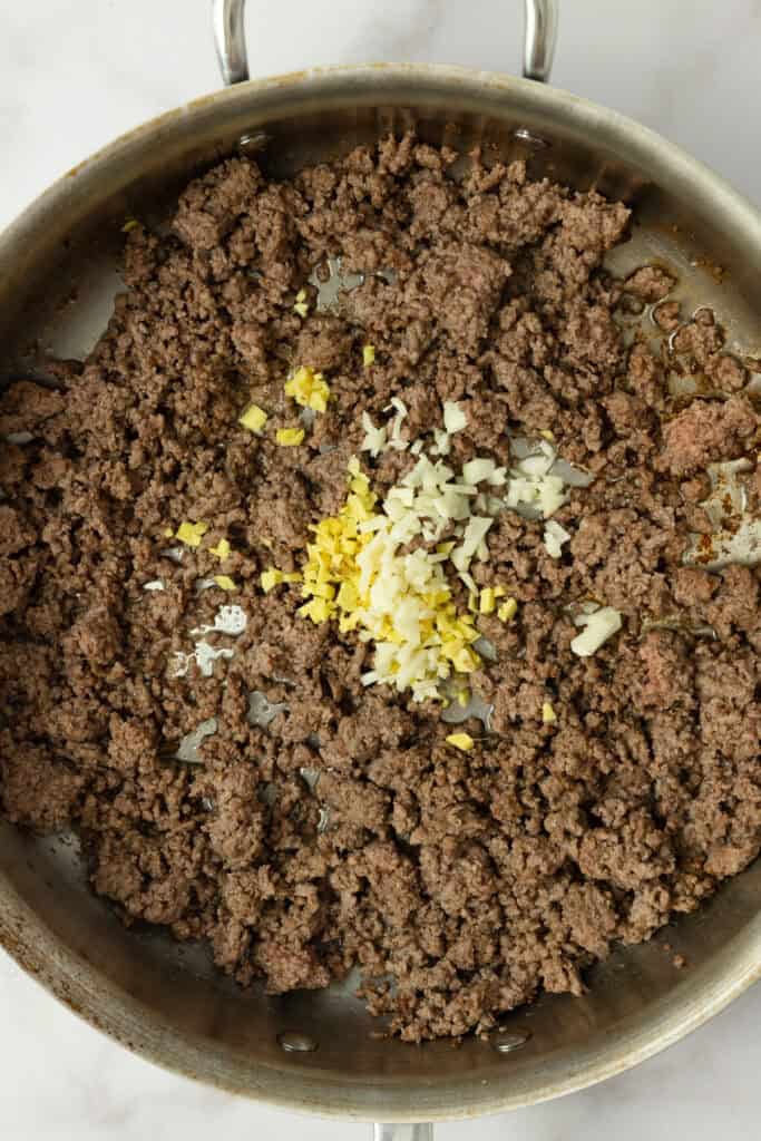 Ginger and garlic added to browned beef in a skillet.