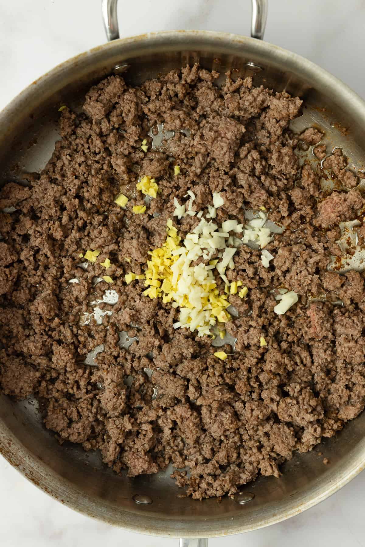 Ginger and garlic added to browned beef in a skillet.