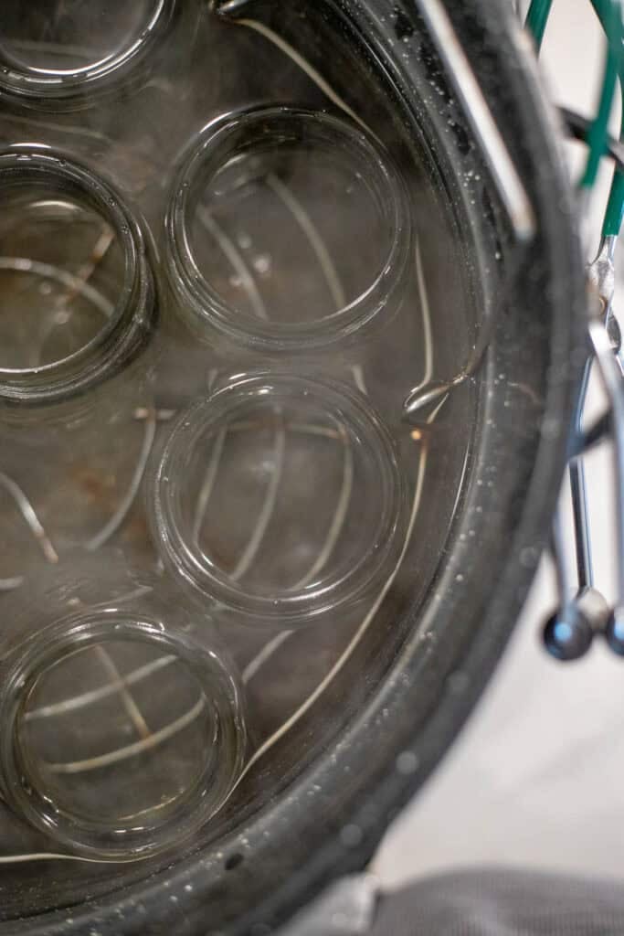 Canning jars simmering in a pot of water on the stove.