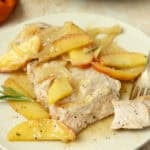 A plate full of pork chop with sautéed apples and onions.