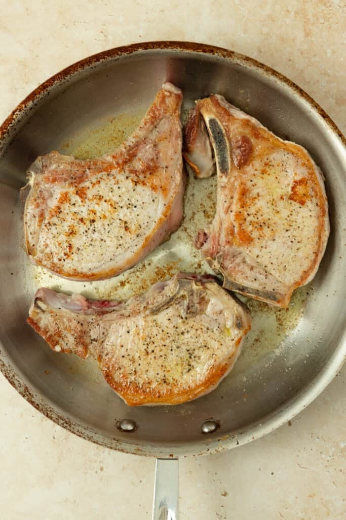 Searing pork chops in a skillet.