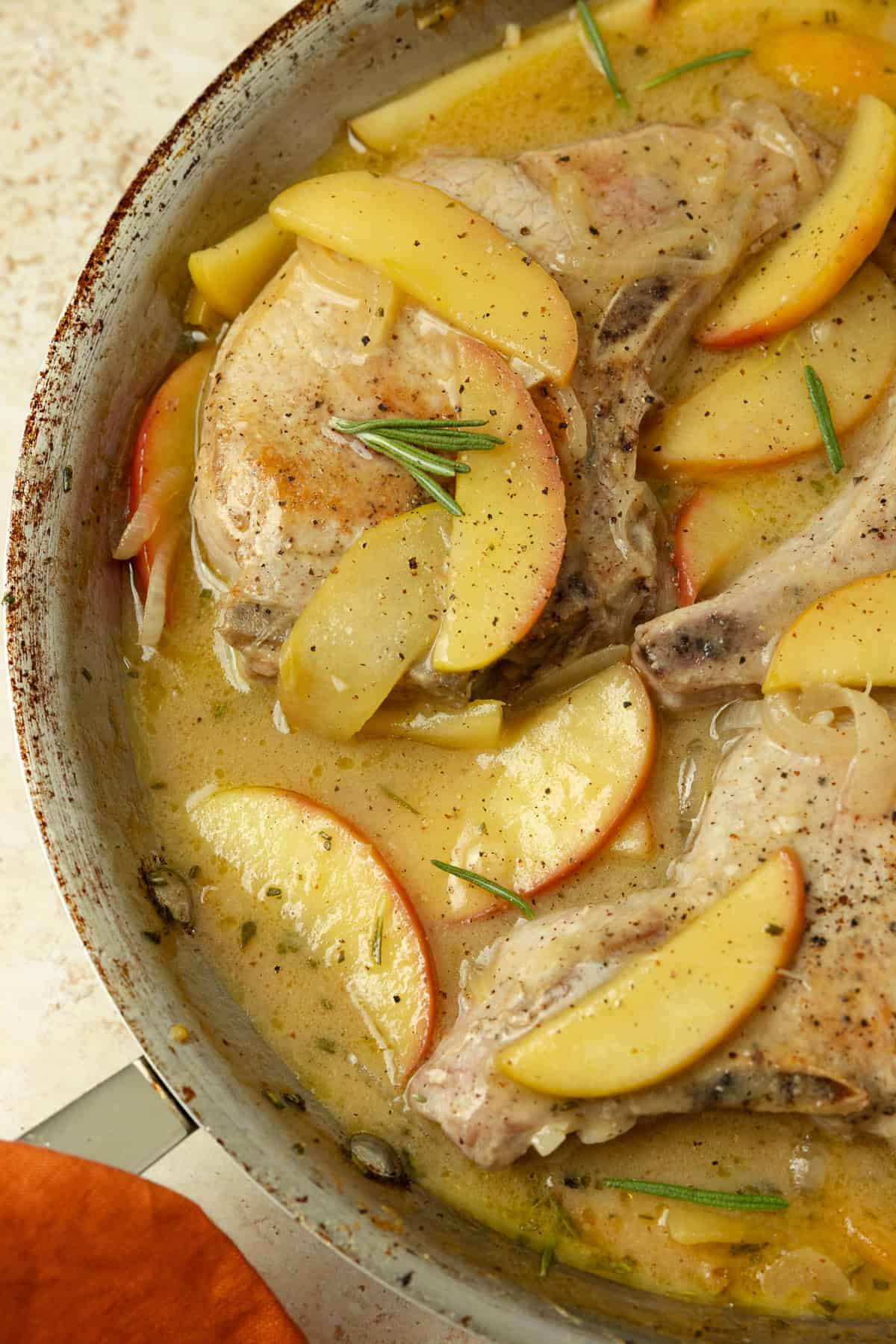 Skillet with pan seared pork chops, sliced onions and apples.