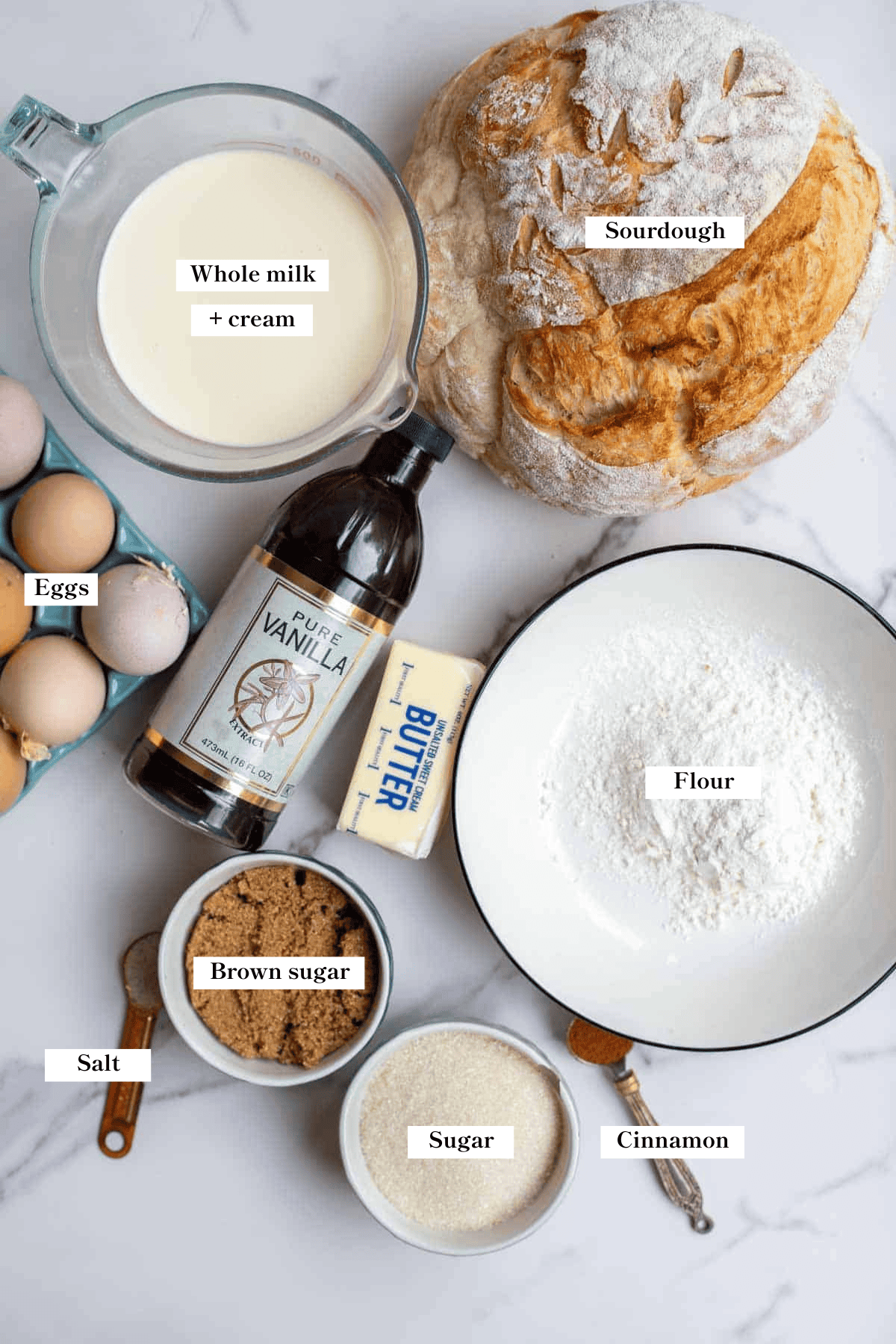 Sourdough bread, whole milk, eggs, vanilla and other ingredients on a countertop.