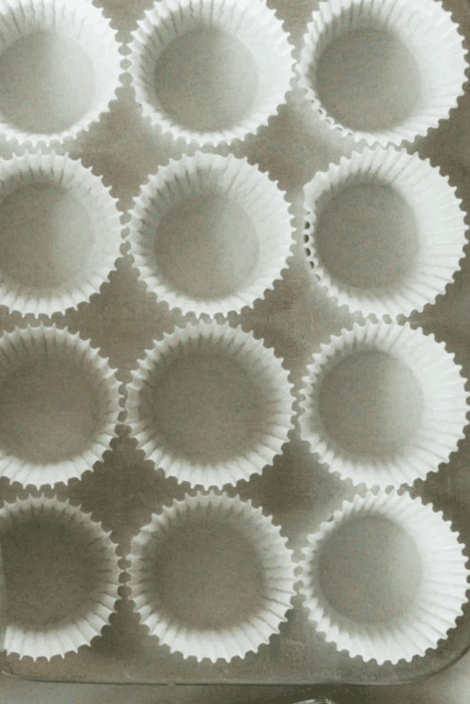 A stainless steel muffin tin with cupcake liners in each spot.