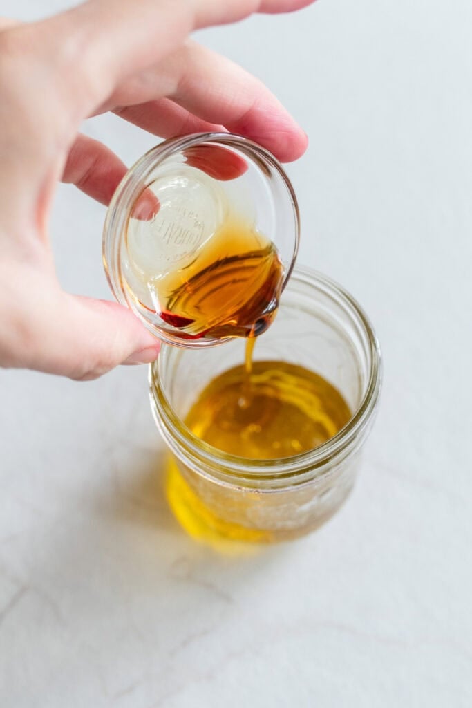 Pouring maple syrup into dressing.