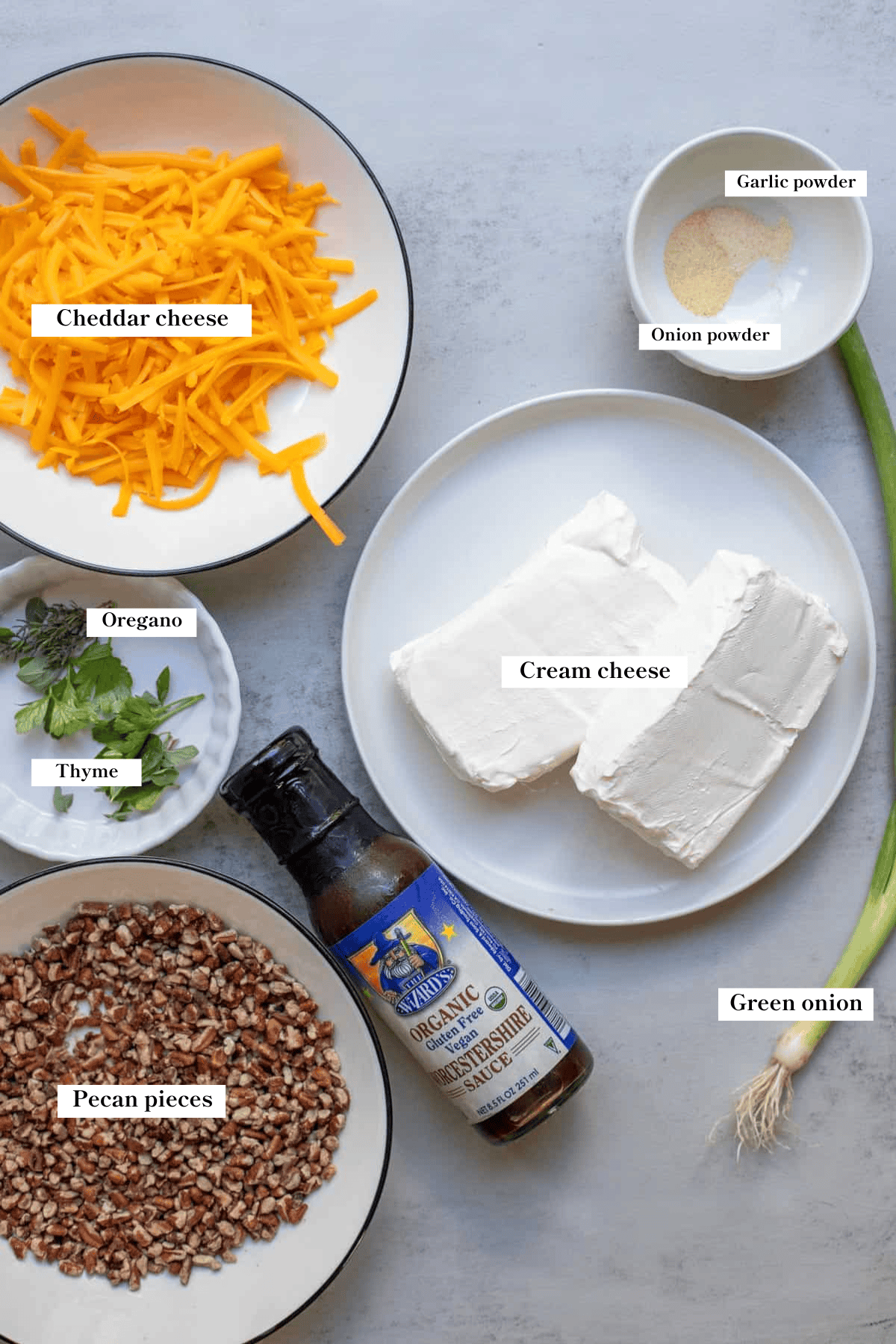 Cheese, cream cheese, seasonings, fresh herbs, and pecan pieces on the counter.