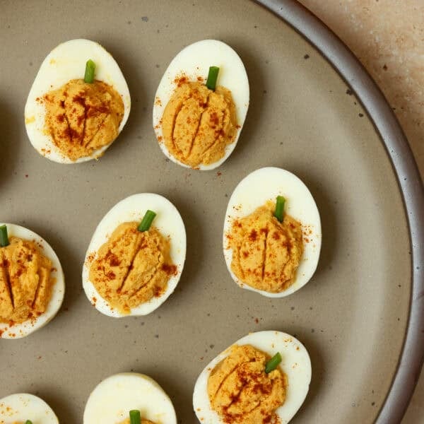 Pumpkin deviled eggs with the egg filling that looks like pumpkin on a plate.