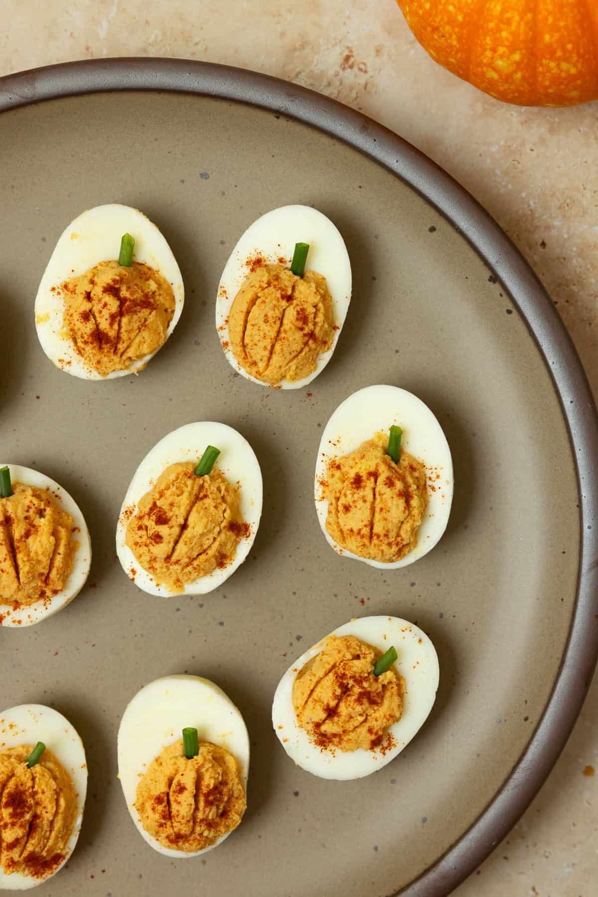 Pumpkin deviled eggs with the egg filling that looks like pumpkin on a plate.