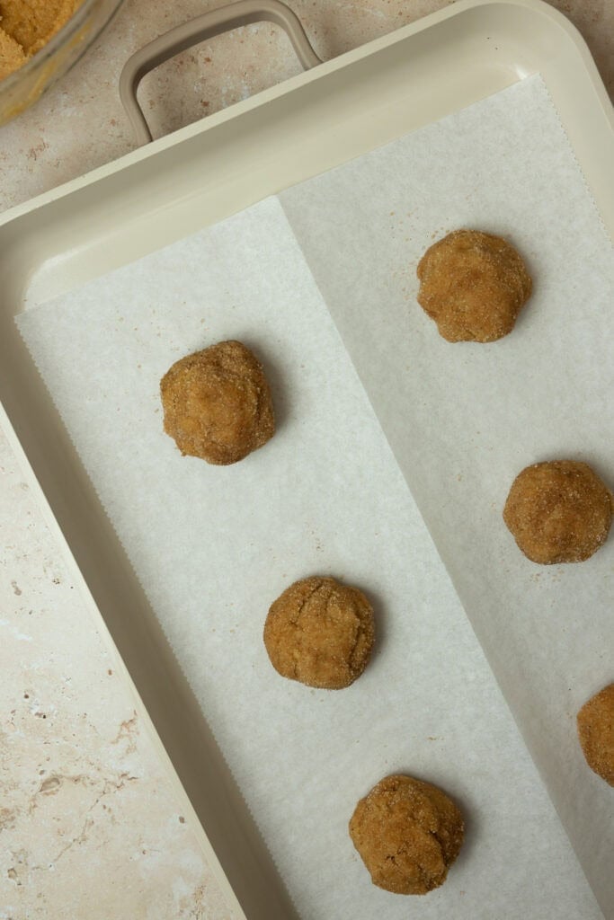 Cookie balls on a parchment lined baking sheet.